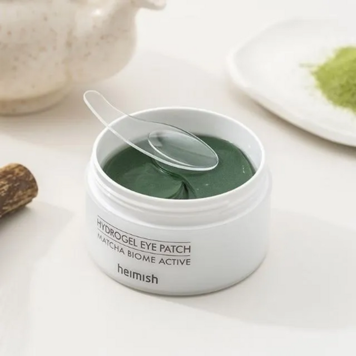 En skål med Heimish Matcha Biome Hydrogel Eye Patch 60 plåster med en sked.